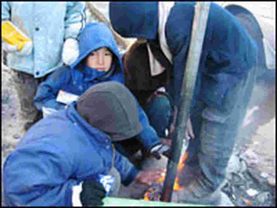 Street kids in Kabul warm themselves by a makeshift fire.