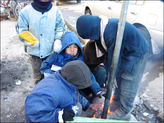 Street kids in Kabul warm themselves by a makeshift fire.