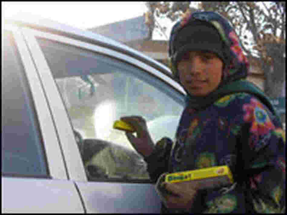Malayeh, 11, tries to hawk gum to a driver on a busy street in Kabul.