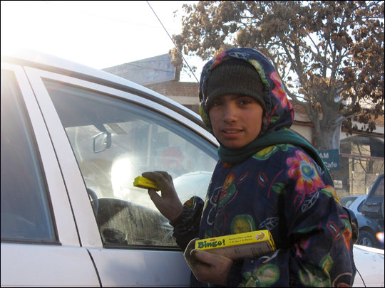 Malayeh, 11, tries to hawk gum to a driver on a busy street in Kabul.