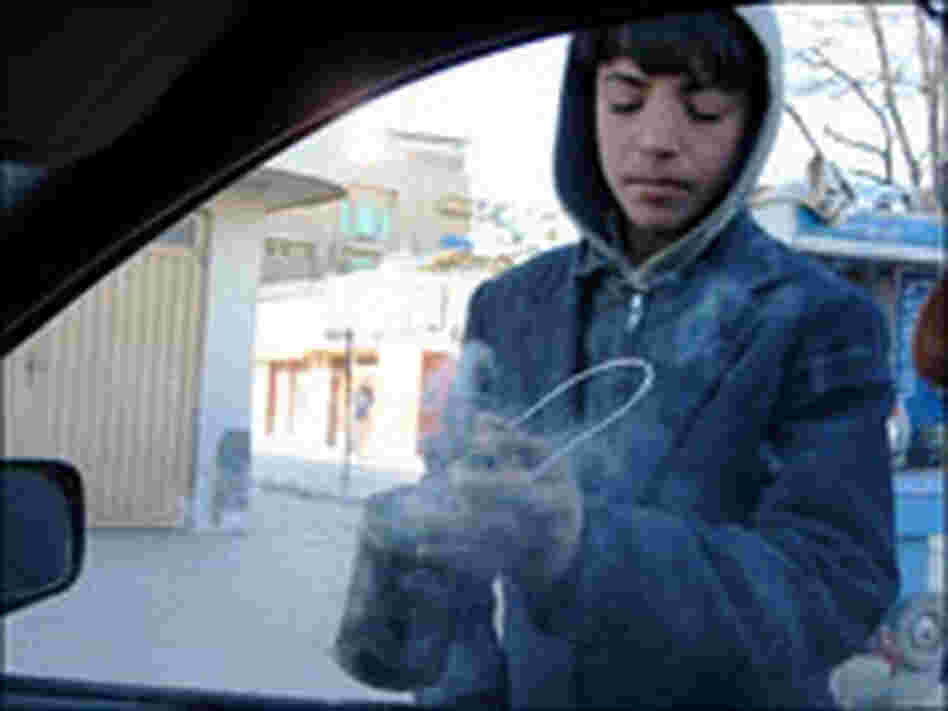 Fahim, 11, waves his can of burning incense inside a car on a busy Kabul street.