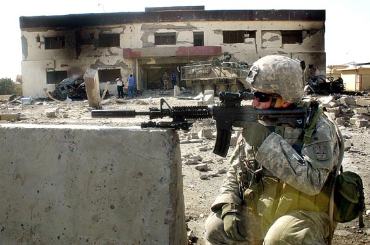 A U.S. soldier secures the area where a suicide car bomb exploded near a police station in Mosul.