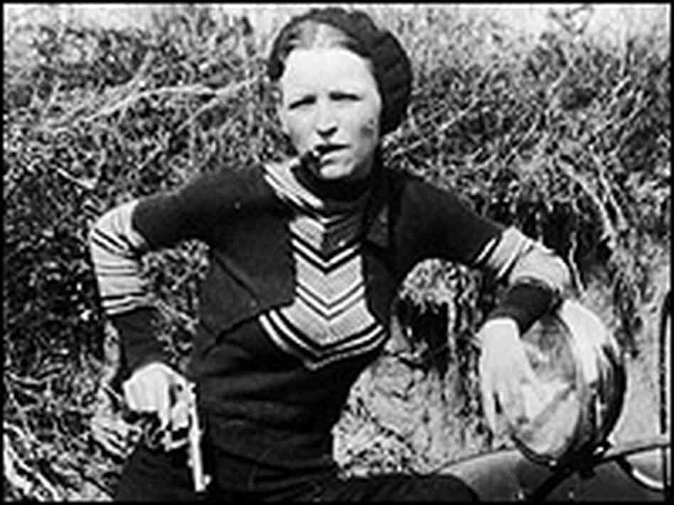 Bonnie Parker smokes a cigar while toting a pistol in this 1930s photo.