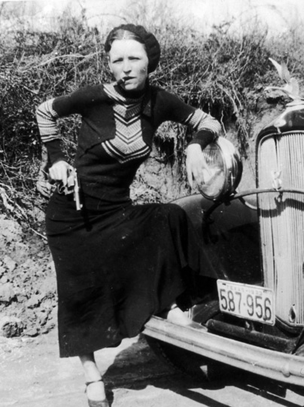 Bonnie Parker smokes a cigar while toting a pistol in this 1930s photo.