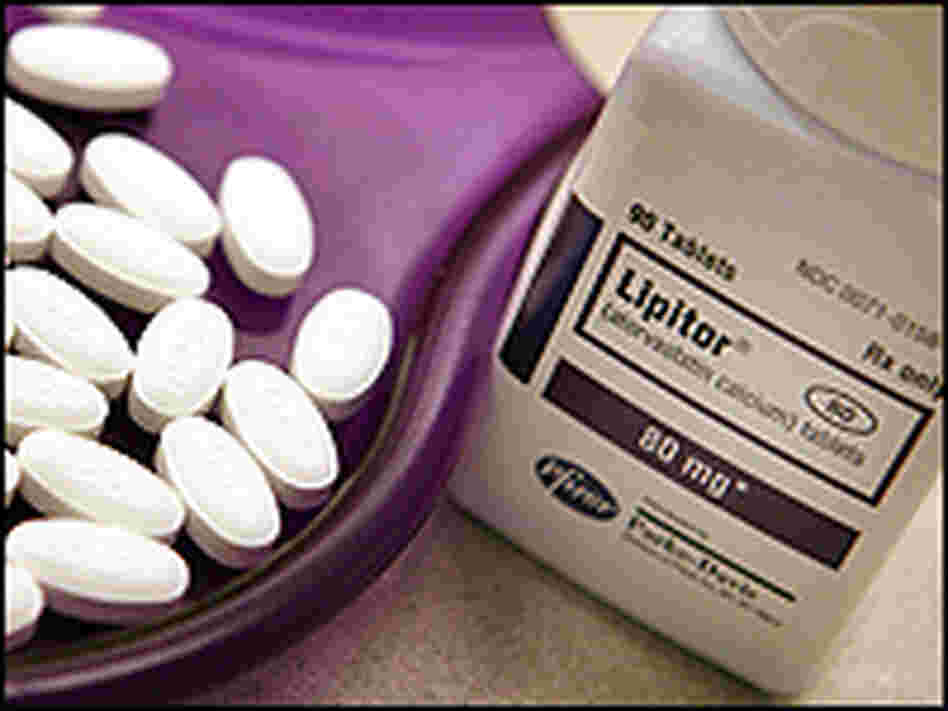 A bottle of Lipitor sits next to some pills in a tray. A bottle of Lipitor sits next to some pills in a tray.