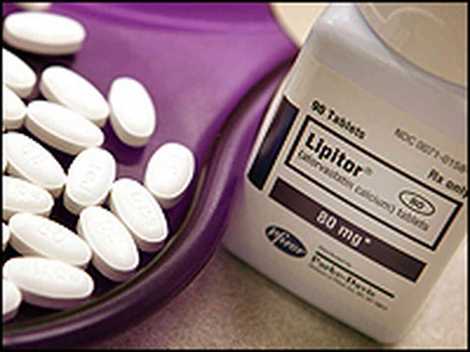 A bottle of Lipitor sits next to some pills in a tray. A bottle of Lipitor sits next to some pills in a tray.