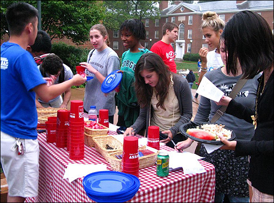 A group of UVA students serve themselves food from a table.