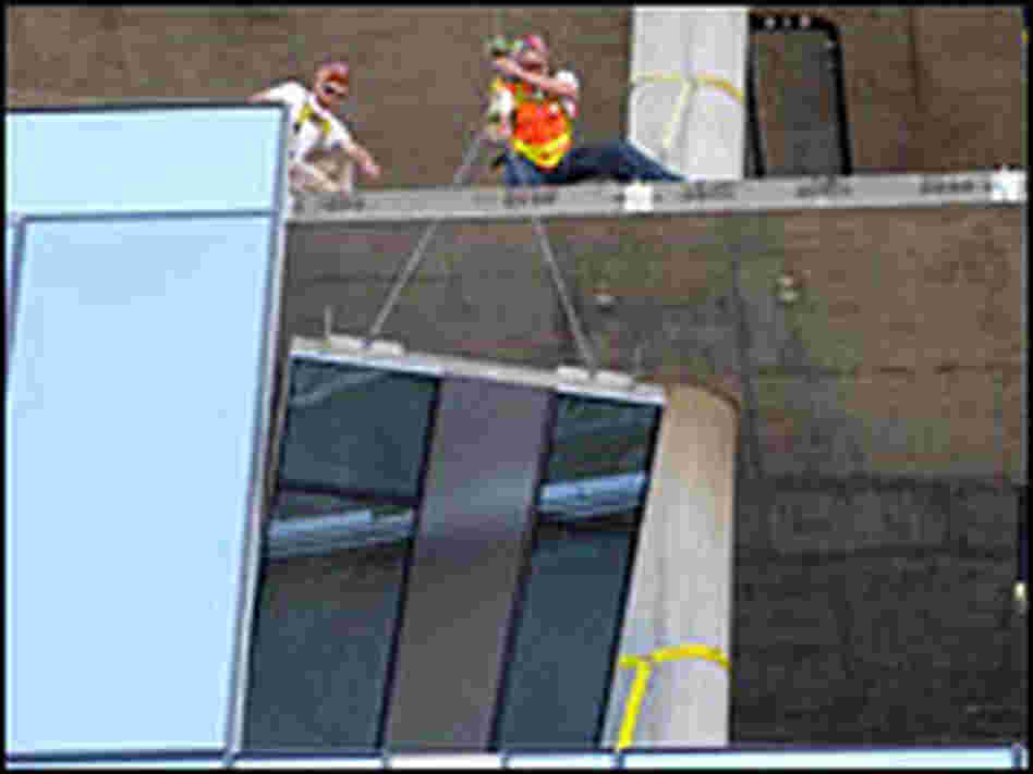 A glass panel is fitted into a building under construction in downtown Portland, Ore.