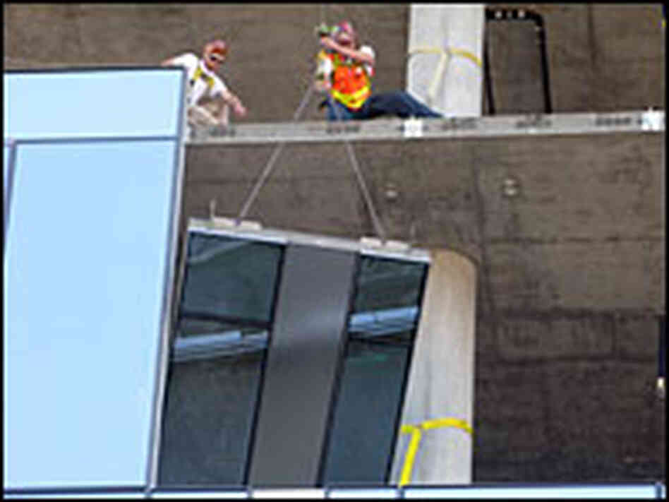 A glass panel is fitted into a building under construction in downtown Portland, Ore.
