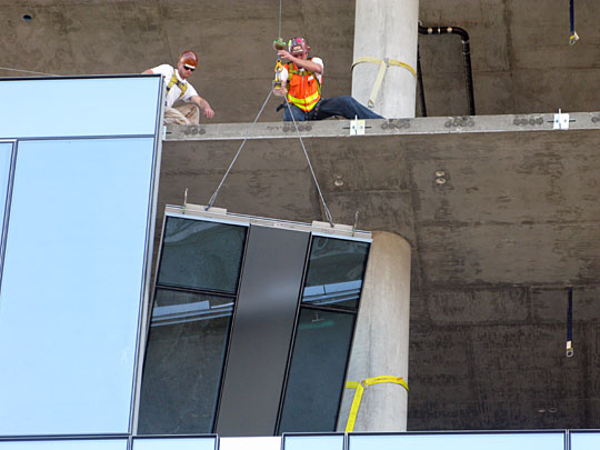 A glass panel is fitted into a building under construction in downtown Portland, Ore.