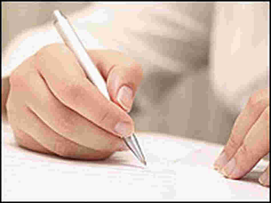 A student writes on a piece of paper A student writes on a piece of paper