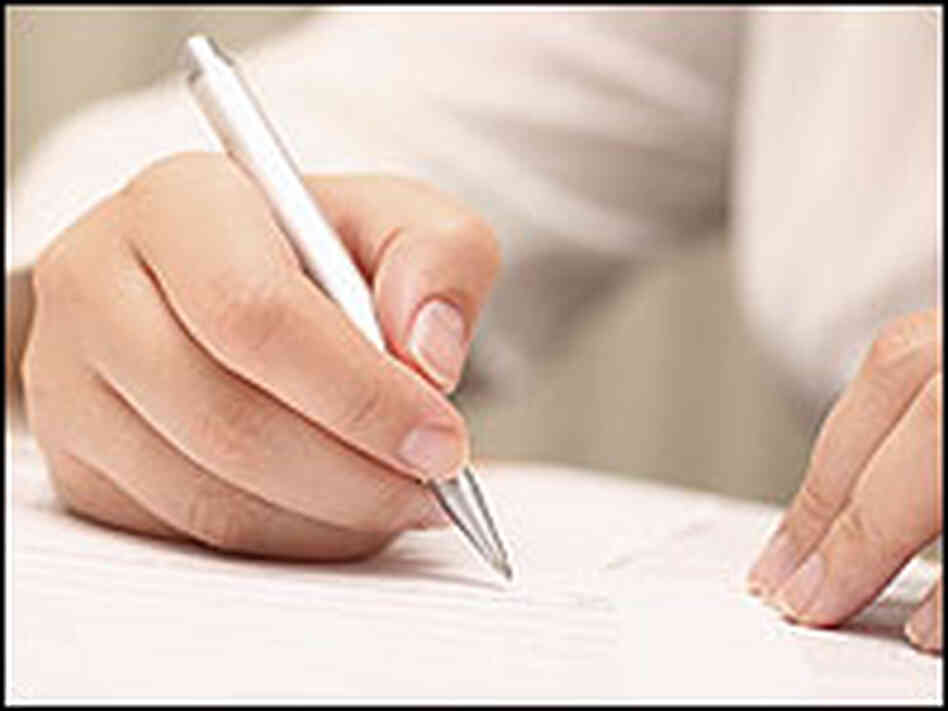 A student writes on a piece of paper A student writes on a piece of paper