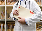 A doctor holds a folder of medical files. A doctor holds a folder of medical files.