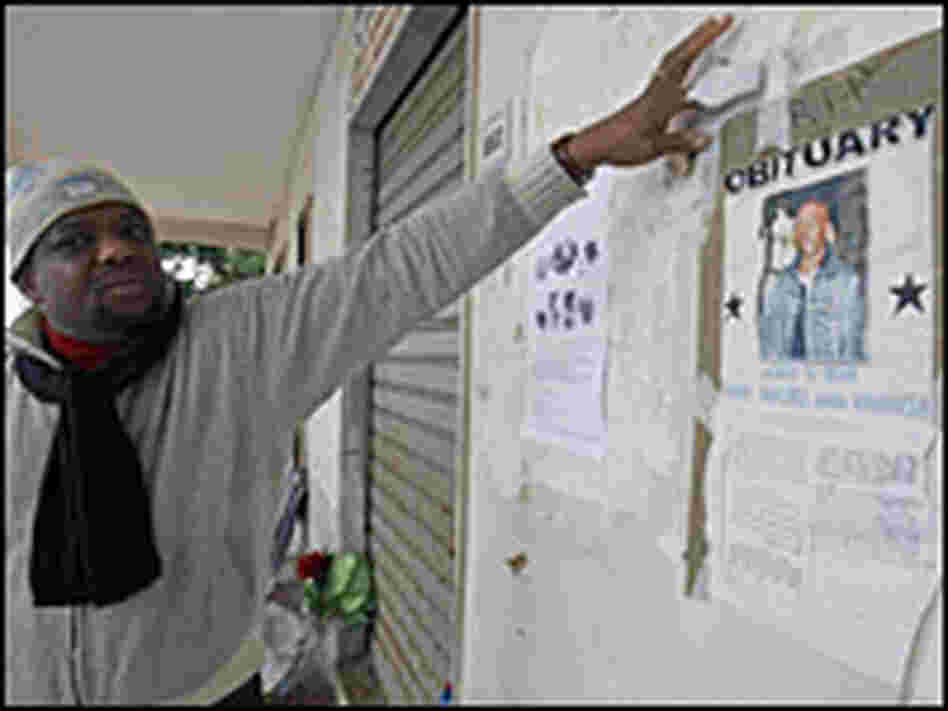 A man points to a poster showing a portrait of Karim Yabuku.