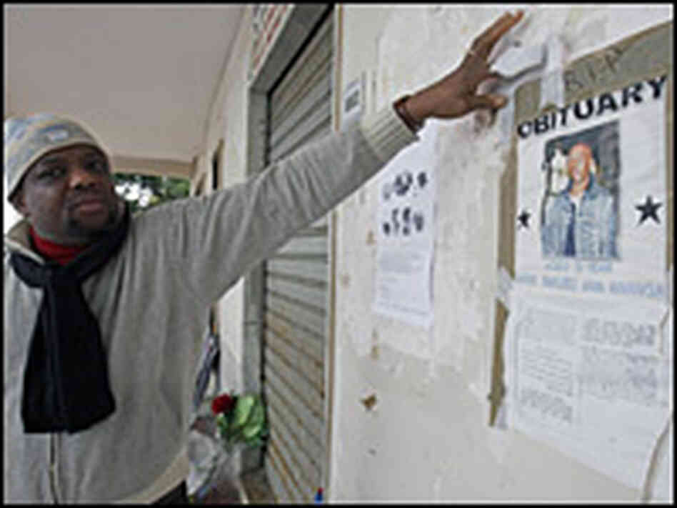 A man points to a poster showing a portrait of Karim Yabuku.