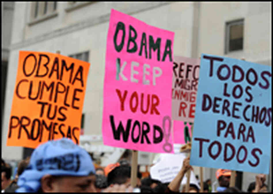 Protesters hold Spanish and English signs at a rally for universal health care reform