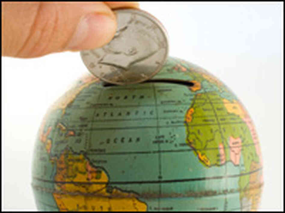 A silver dollar being placed into a globe bank. A silver dollar being placed into a globe bank.