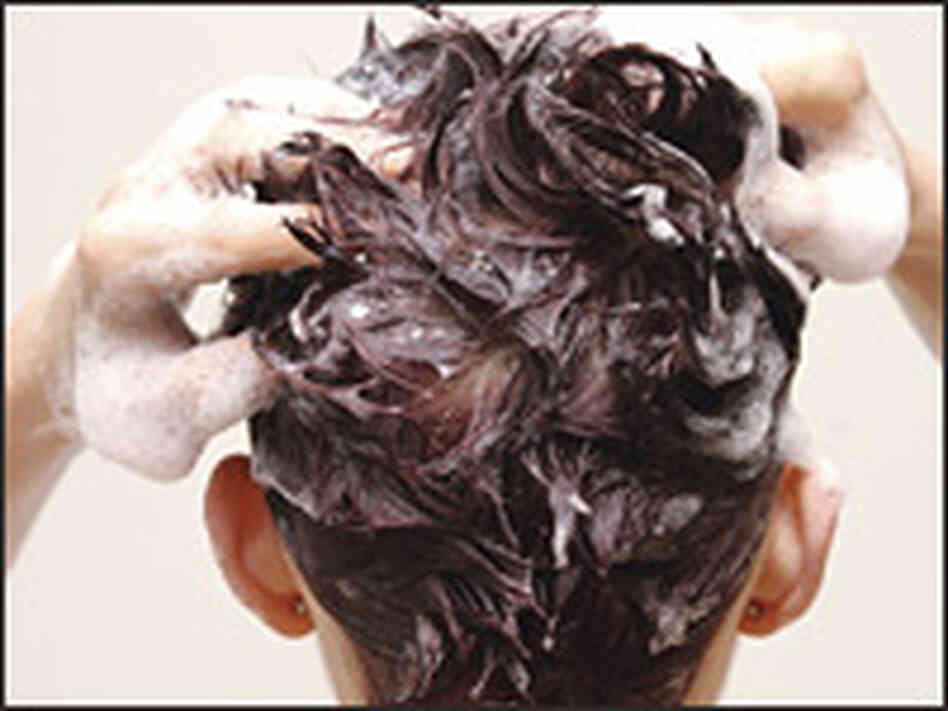 A woman lathers up her hair with shampoo. A woman lathers up her hair with shampoo.