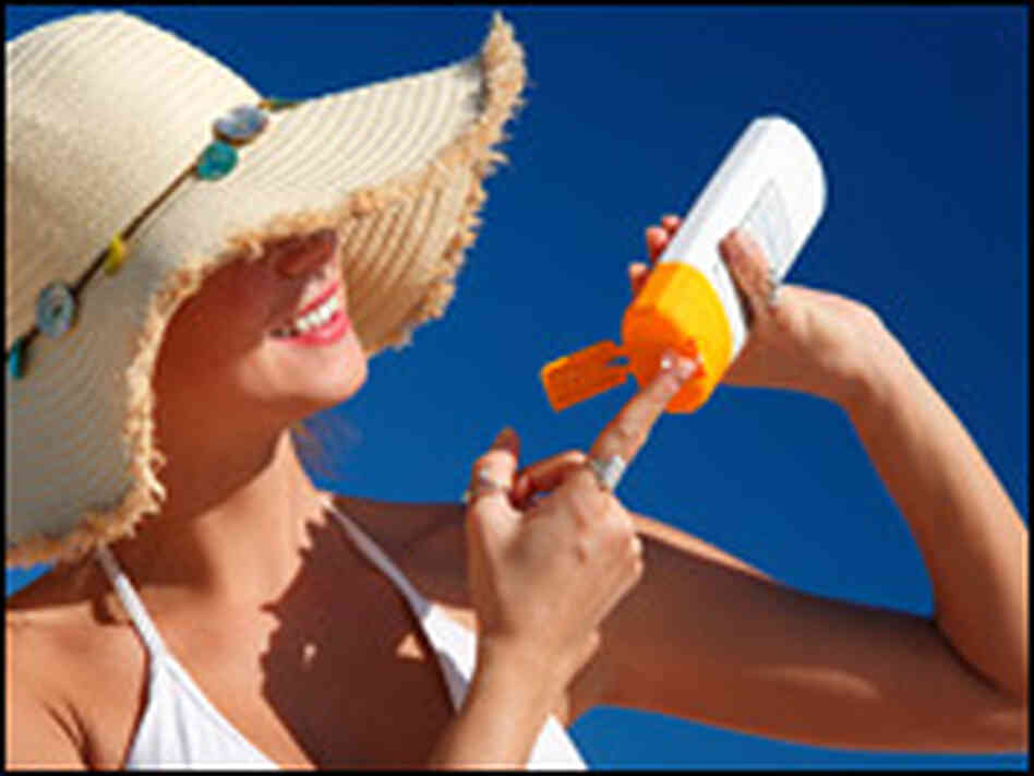 A woman wearing a beach hat puts on sunscreen. A woman wearing a beach hat puts on sunscreen.