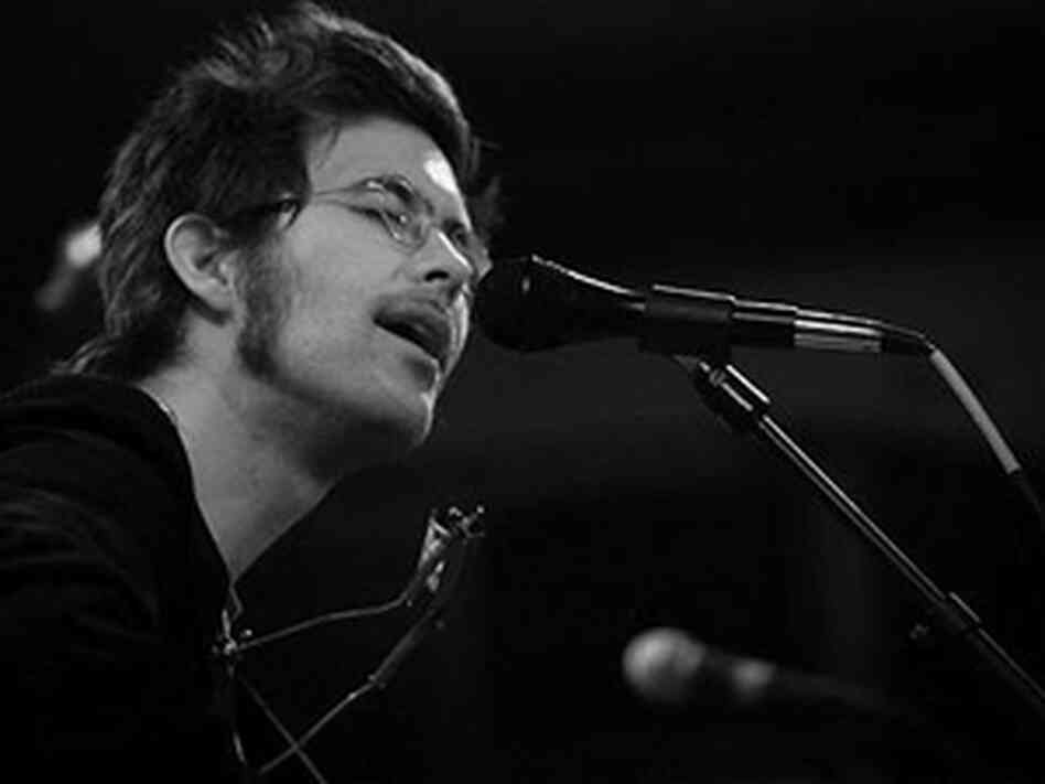 Elvis Perkins sings into a microphone. Elvis Perkins sings into a microphone.