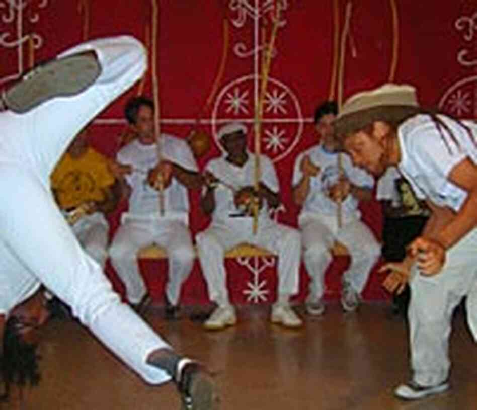 The mestre (in center background) plays while watching a capoeira game.