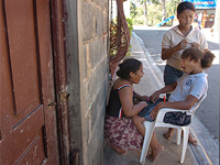 Angela Martinez, 12, left, entertains friend Estefany Diaz, 10, as Estefany's sister Ariela does her hair in the Paraiso de Dios neighborhood west of Santo Domingo.