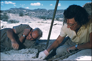 Dr. Louis Leakey lies on the ground to dig, 
	while his wife Mary sits and digs next to him. The two were at Tanzania's 
	Olduvai Gorge on a National Geographic expedition.