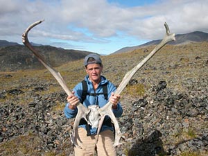 NPR's Elizabeth Arnold holds a caribou skull 
		with massive antlers still attached.