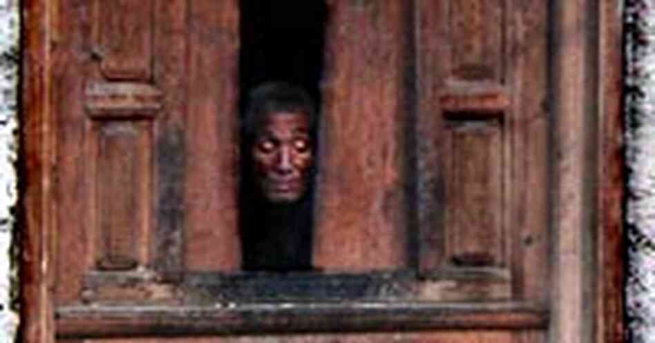 A Gebu village resident peeks from his window down at the street below.