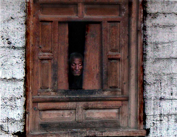 A Gebu village resident peeks from his window down at the street below.