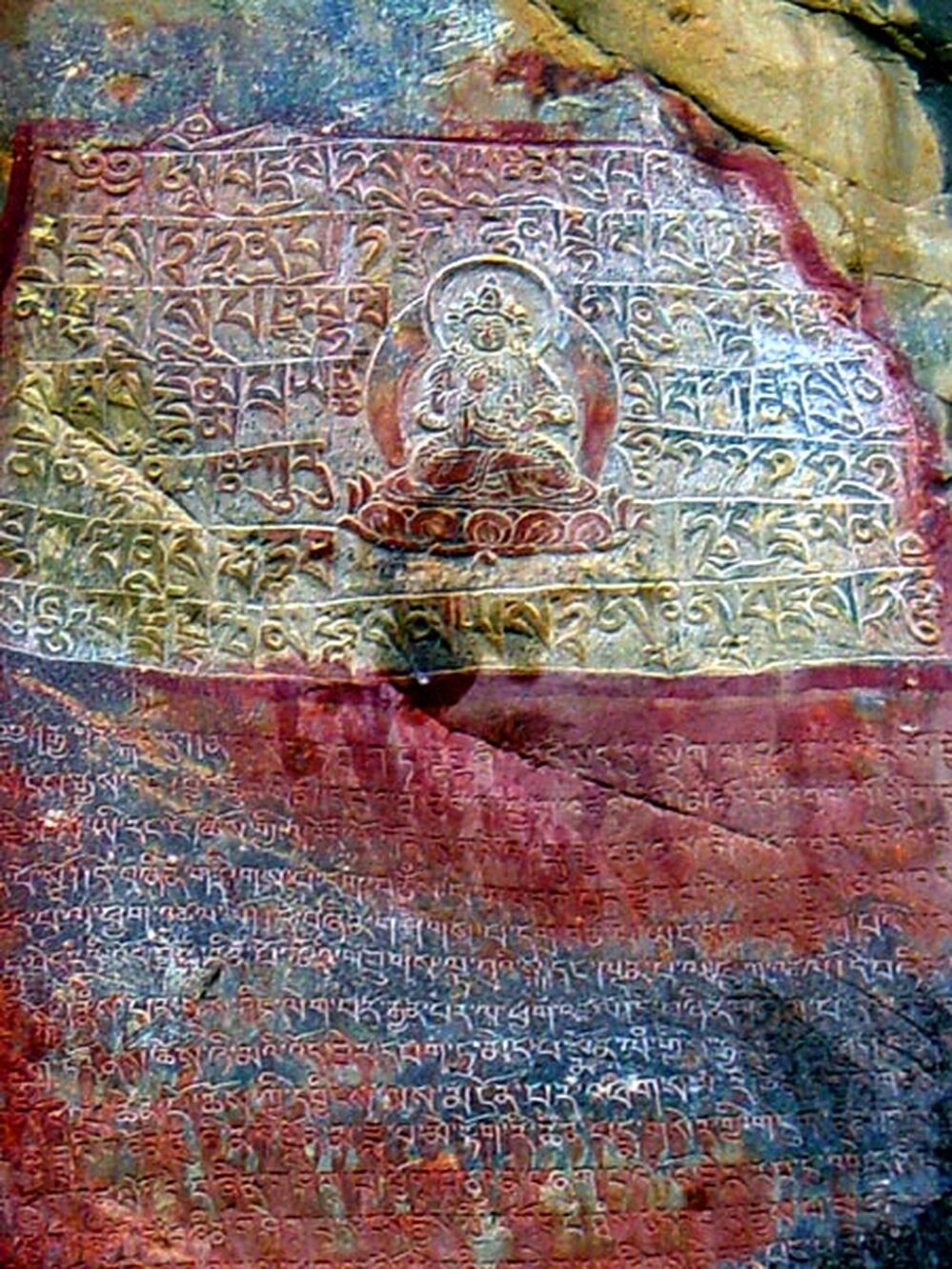 Image of Buddha with prayers in Tibetan script inscribed into the mountain rock