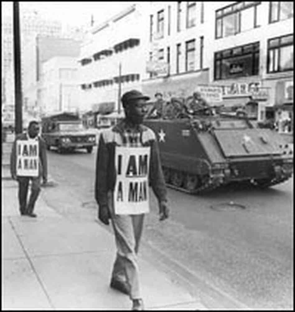 Striking sanitation workers march in Memphis in 1968, escorted by the National Guard.