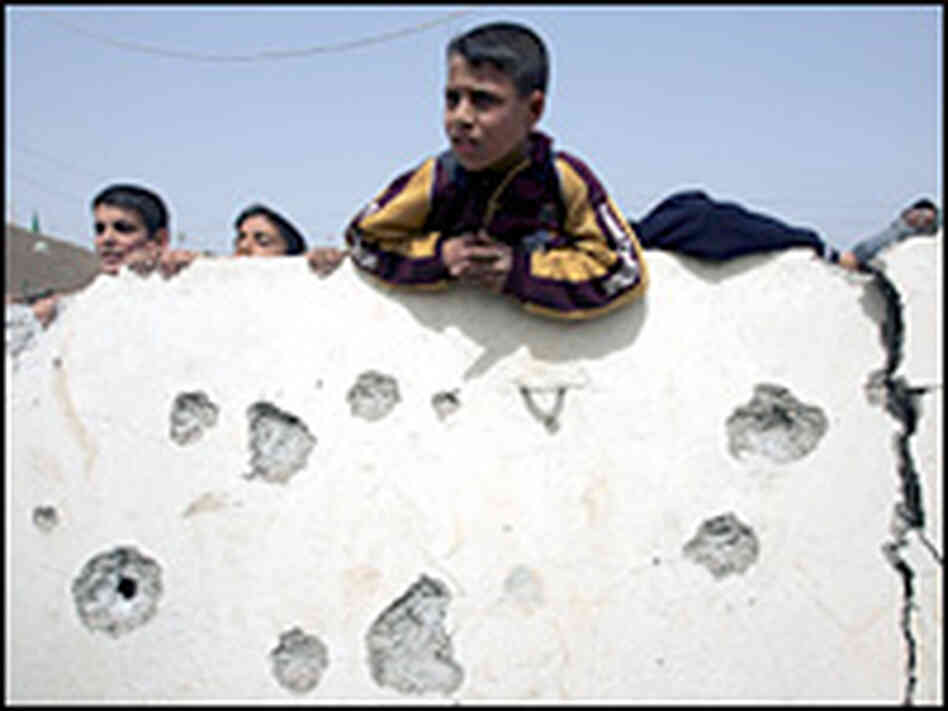 Iraqi children climb on a partially damaged wall after a mortar attack inside their school grounds. Iraqi children climb on a partially damaged wall after a mortar attack inside their school grounds.