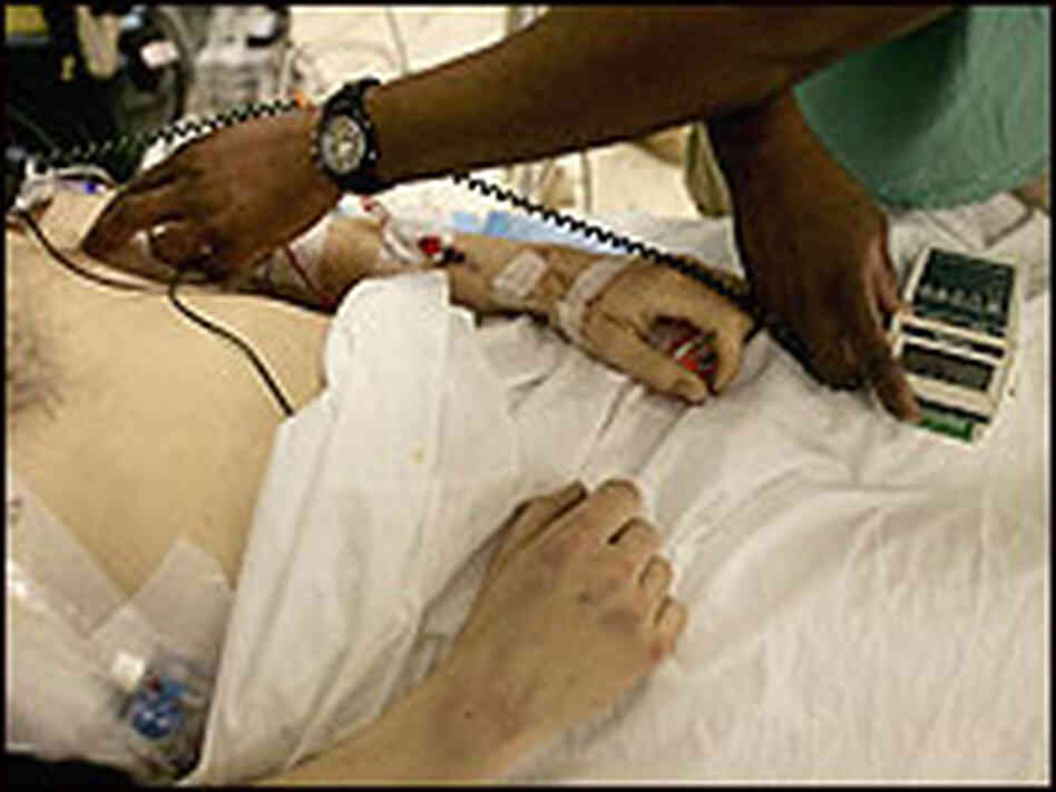 Hospital staff member takes a reading from the chest of a wounded soldier. Hospital staff member takes a reading from the chest of a wounded soldier.