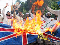 Pakistani Muslims torch a Britain flag as they shout slogans during a protest in Lahore, condemning the title of Sir awarded to Salman Rushdie.