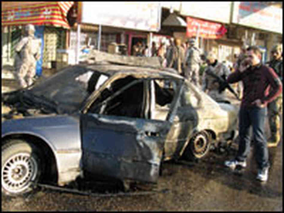 NPR Baghdad bureau translator Ali Hamdani stands beside the wreckage of NPR's armored BMW.