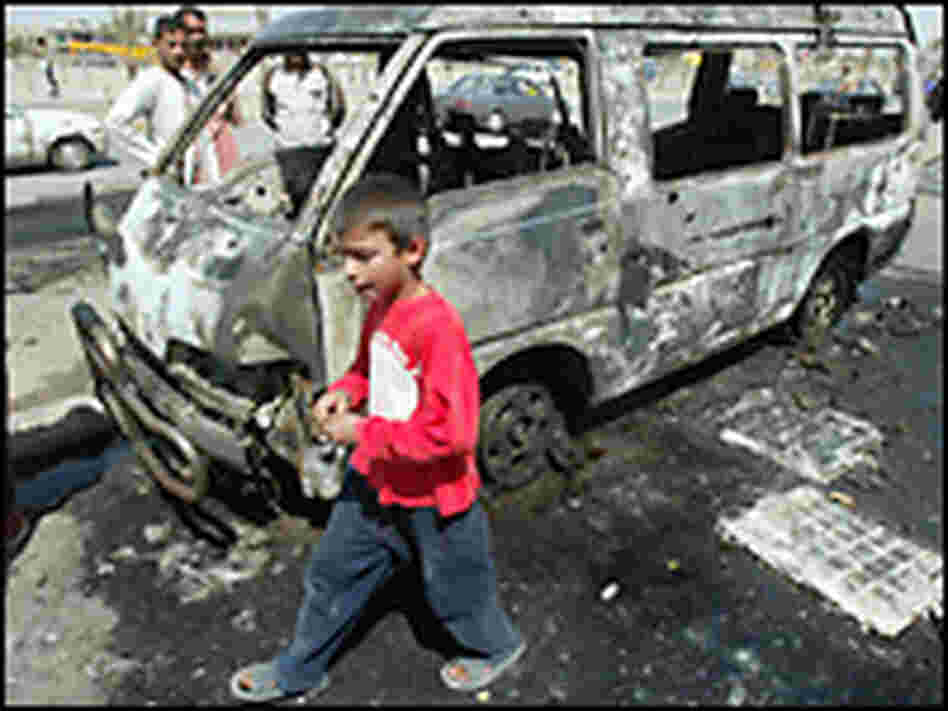 An Iraqi boy walks past bomb wreckage. Credit: WISAM SAMI/AFP/Getty Images.