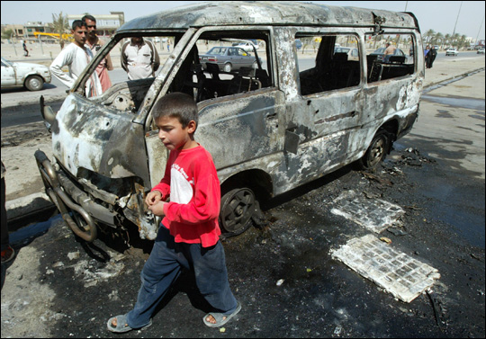 An Iraqi boy walks past bomb wreckage. Credit: WISAM SAMI/AFP/Getty Images.