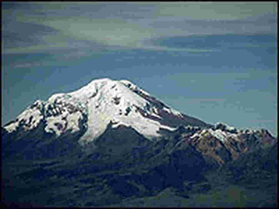 The snow-capped peak of Mount Chimborazo in Ecuador against a bright blue sky.