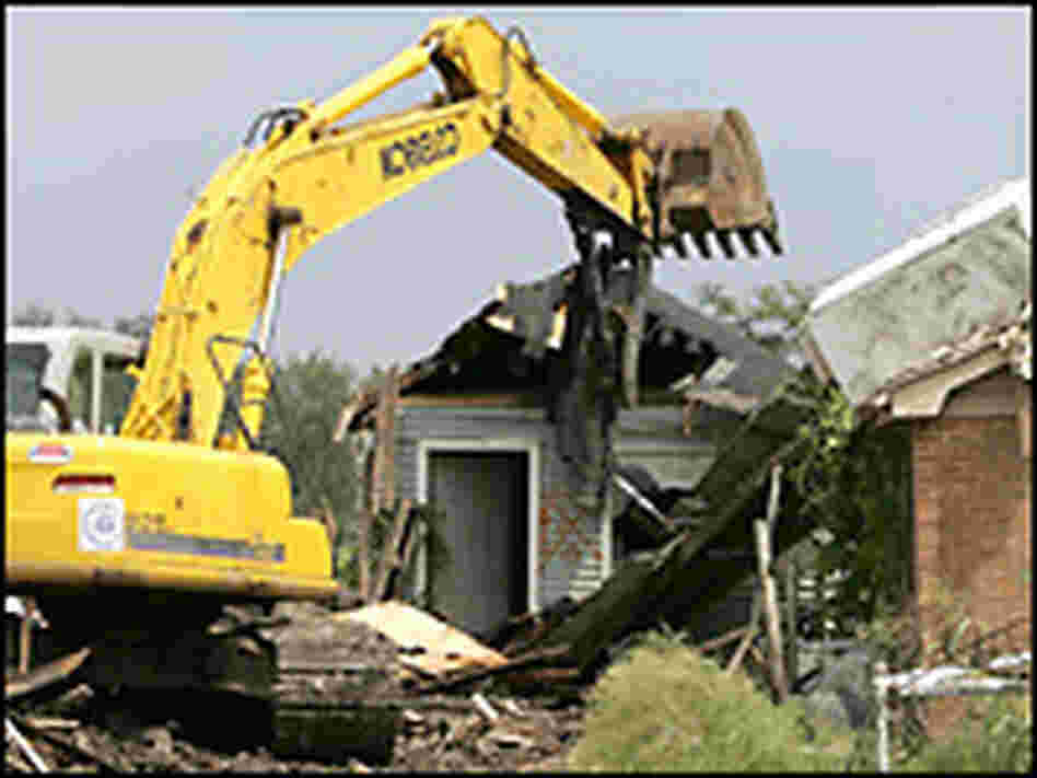 Workers use an excavator to destroy a flood-damaged home. Credit: Justin Sullivan/Getty Images.