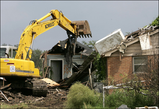 Workers use an excavator to destroy a flood-damaged home. Credit: Justin Sullivan/Getty Images.