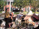 Times-Picayune features writer Renee Peck standing next to a debris pile from her home.
