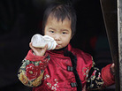 A young child drinks milk outside his home in a hutong in Beijing. A young child drinks milk outside his home in a hutong in Beijing.