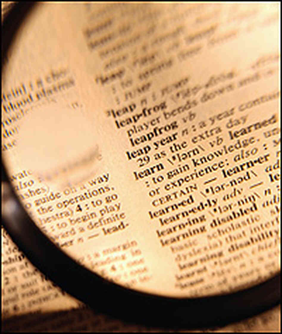 Magnifying glass held over dictionary