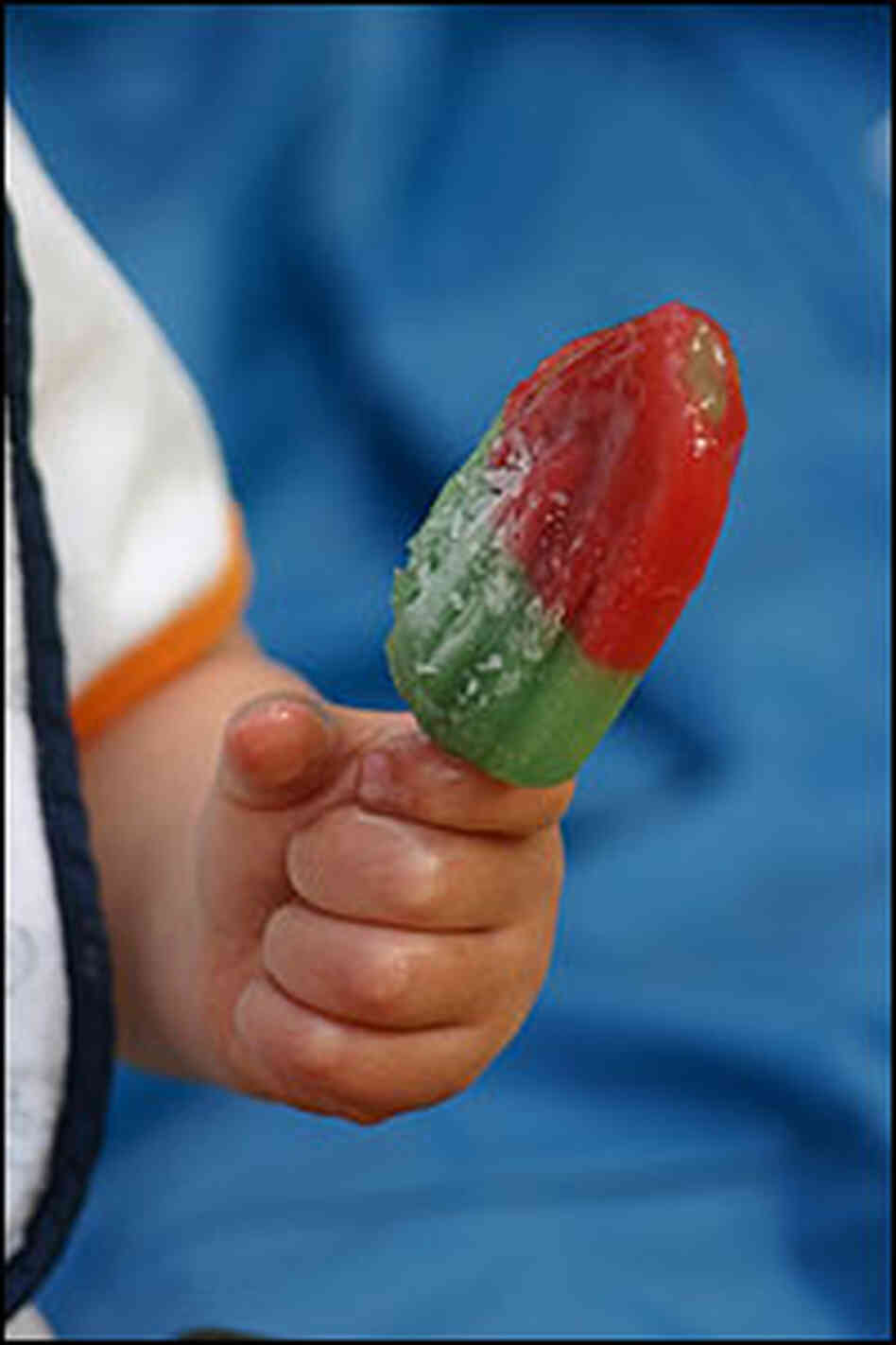 Child holds tri-colored "rocket pop" popsicle. Child holds tri-colored "rocket pop" popsicle.