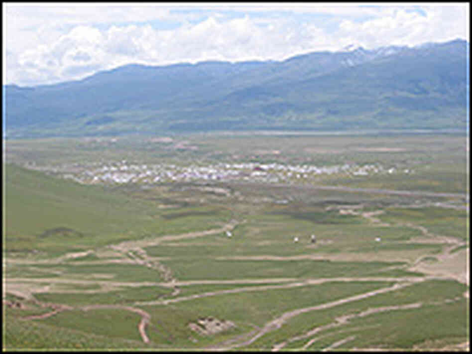 White tents, tiny in the vast distance, cluster on the plain of Kham.