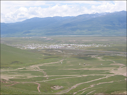 White tents, tiny in the vast distance, cluster on the plain of Kham.
