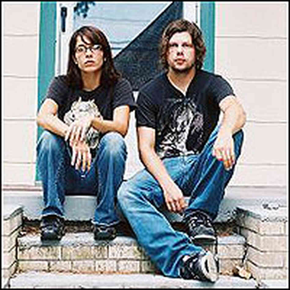 Tessie Brunet and Dax Riggs sit on steps outside a small house. Tessie Brunet and Dax Riggs sit on steps outside a small house.