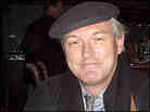 Christopher Buckley, photographed wearing a cap inside a dark bar.