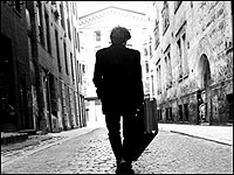 Willie Nile walks between two large buildings on the streets of New York. Willie Nile walks between two large buildings on the streets of New York.